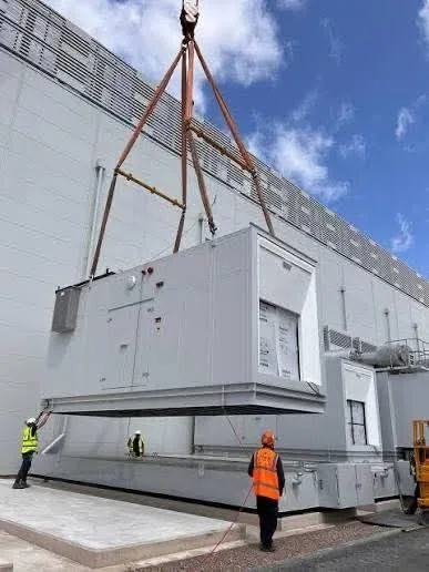 Crane rigging a generator set with a hi-vis crew on site