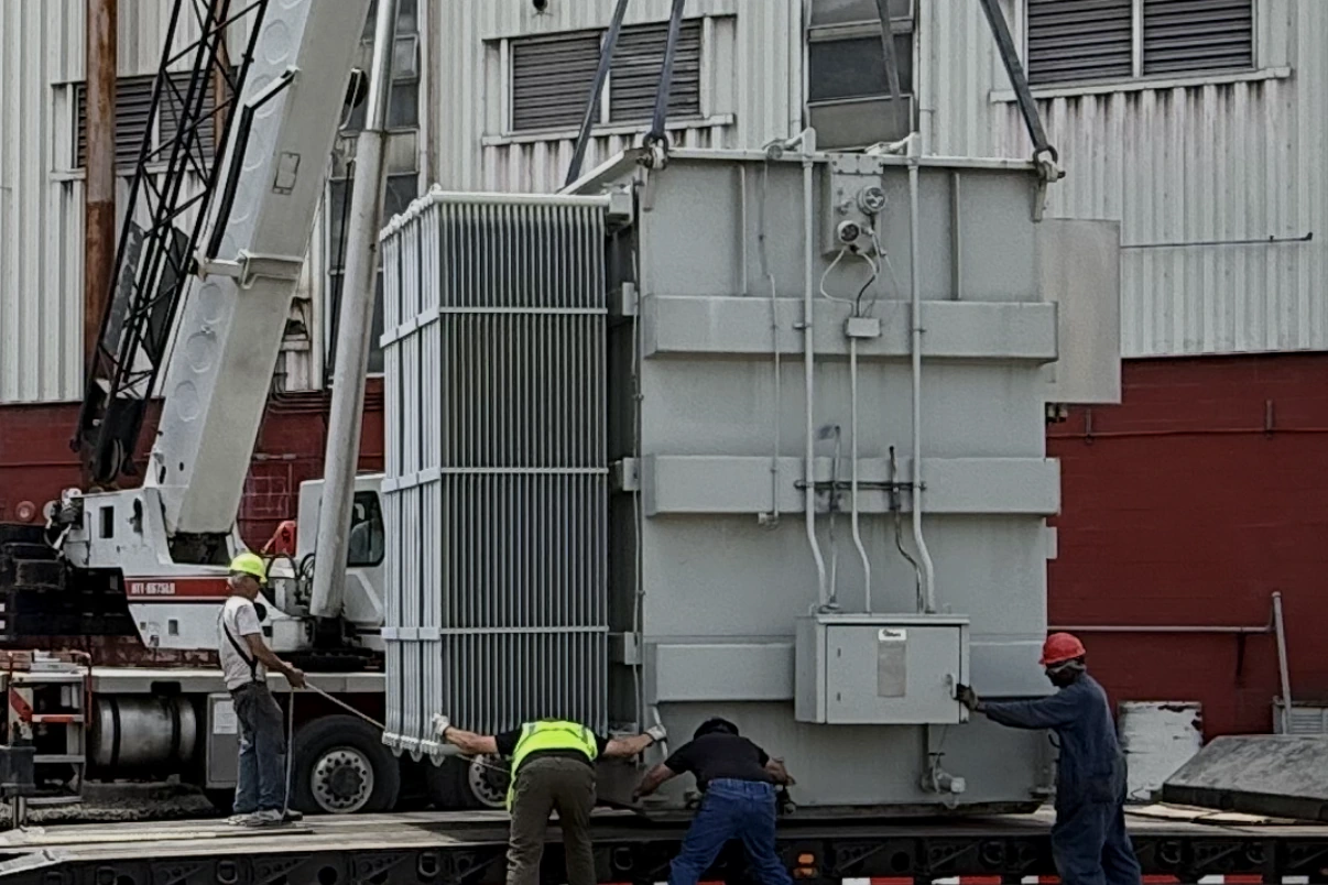 Crane lifting a power transformer onto a lowboy trailer while the removal crew guides the load — Nashville, TN